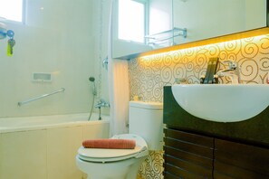 Bathroom features a bathtub, toilet, and sink, with a patterned wallpaper and mirror above the sink.