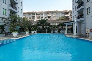Relax by the rectangular pool surrounded by lush greenery and a pergola.