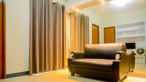 A modern living room with a leather sofa, a flat-screen TV, and a white entertainment unit. - Gading Greenhill 2BR Apartment near Singapore International School (Jakarta)