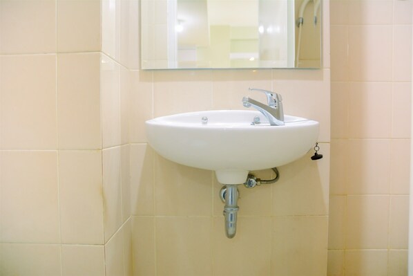 Bathroom features a wall-mounted sink with a chrome faucet and a rectangular mirror above.