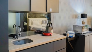 A modern kitchen with a sink, a red electric kettle, a microwave, and a kettle on the counter.
