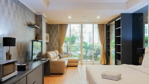 A modern hotel room with a large bed, a sofa, a TV, and a balcony with curtains.