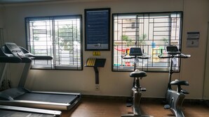 A fitness room with treadmills and stationary bikes, large windows with metal bars, and a poster on the wall. - 2BR for 3 Pax Mediterania Marina Ancol Apartment (Jakarta)