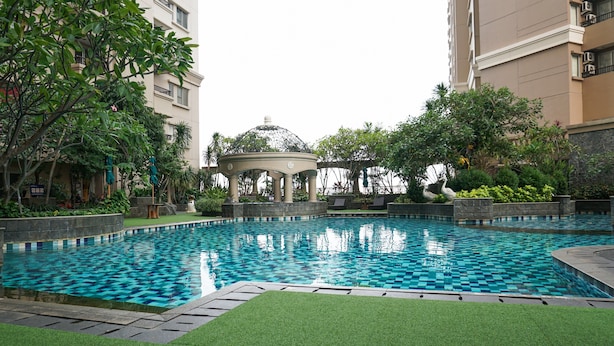 A swimming pool with a checkered pattern, surrounded by greenery and a gazebo. - 2BR for 3 Pax Mediterania Marina Ancol Apartment (Jakarta)