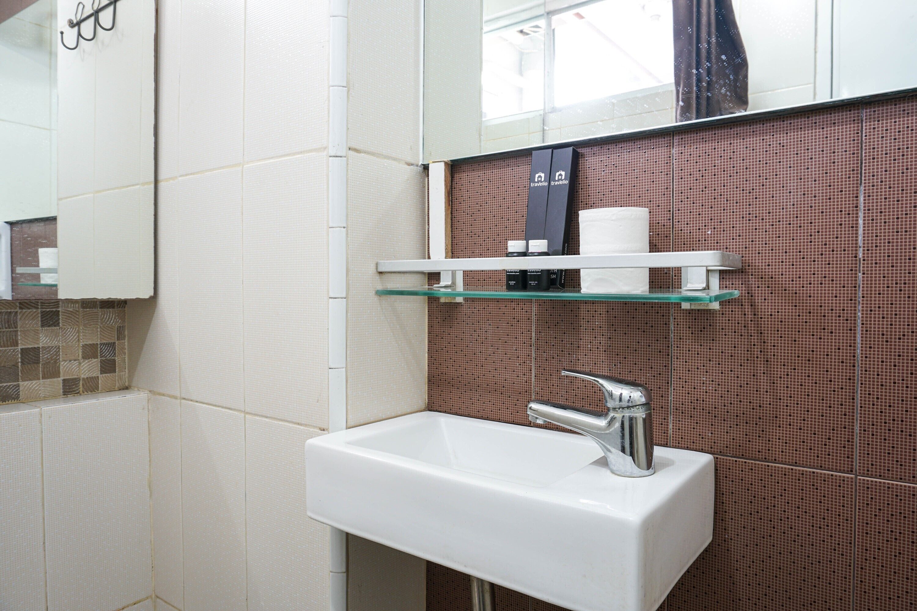 A bathroom with a white sink, a mirror, and a shelf with toiletries.