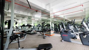 A gym with various exercise machines, mirrors, and a carpeted floor.