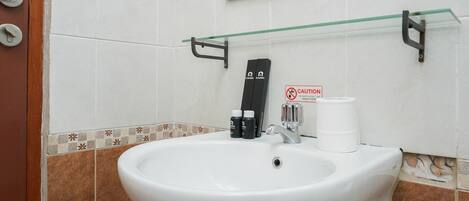 A bathroom with a white sink, a mirror, a framed mirror above, and a caution sign on the wall.
