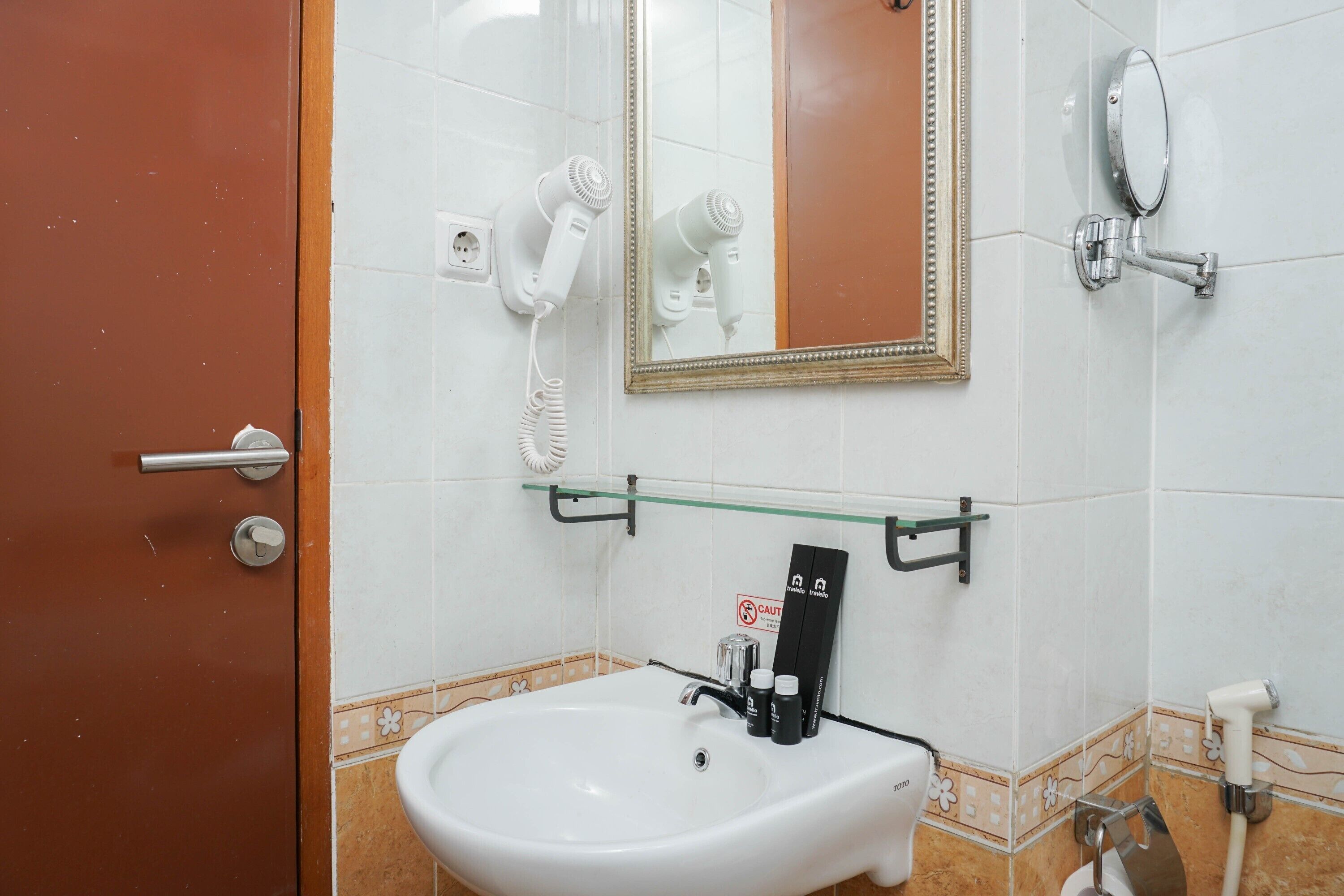 A bathroom with a white sink, a mirror, a hairdryer, and a towel rack.