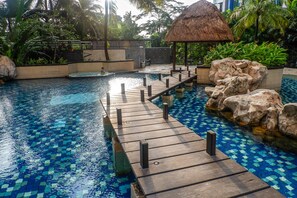 Ein Pool mit Holzterrasse und einem strohgedeckten Gebäude.