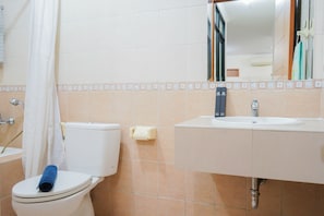 A bathroom with a toilet, a sink, and a shower curtain. - Elegant and Homey 2BR Hampton's Park Apartment (Jakarta)
