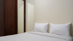 A neatly made bed with white linens and pillows, a wooden door to the left, and a plain wall. - Elegant and Homey 2BR Hampton's Park Apartment (Jakarta)