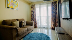 Una sala de estar con un sofá marrón, una alfombra azul, un cuadro en la pared y un televisor en la pared.