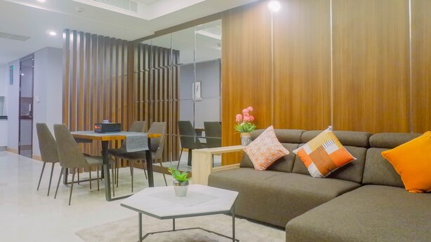 A modern living room with a sofa, a coffee table, and a dining area with chairs and a table.