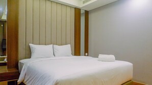 A neatly made bed with white linens in a hotel room.
