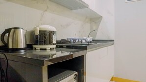 A modern kitchen with a marble backsplash, stainless steel kettle, coffee maker, and a built-in oven.