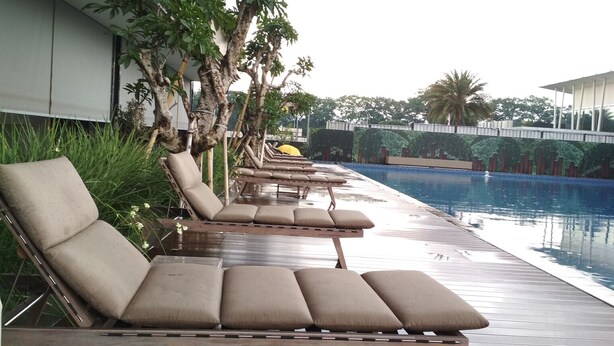 A poolside area with lounge chairs and a pool. - Gorgeous 3BR Apartment at Landmark Residence near 23 Paskal (Bandung)