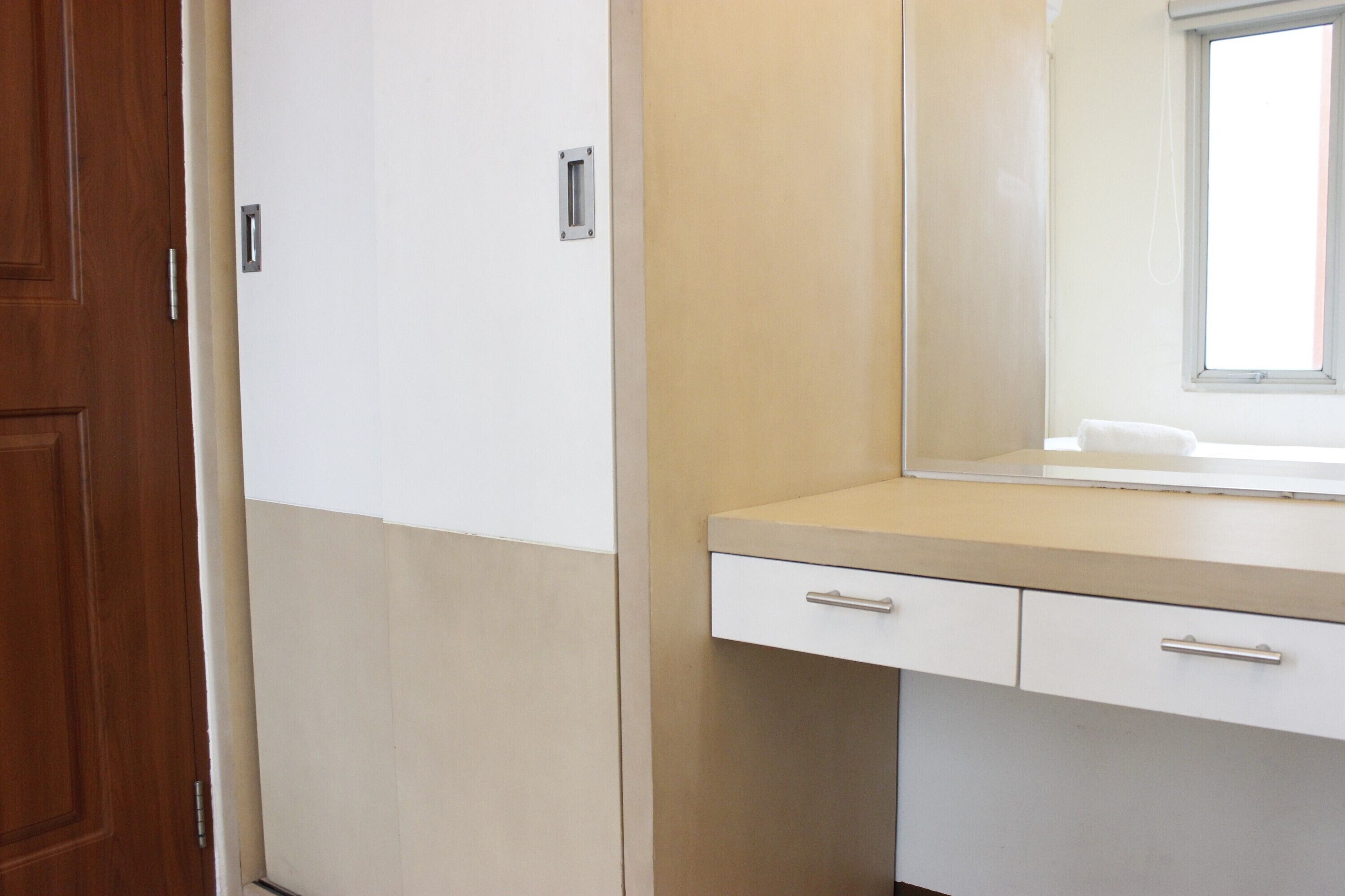 Un baño con puerta de madera, un mueble blanco y un espejo sobre una encimera.