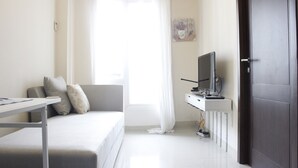 A modern, well-lit room with a sofa, a desk with a computer, and a television. - Compact 2BR @ Galeri Ciumbuleuit 2 Apartment near Dago (Bandung)