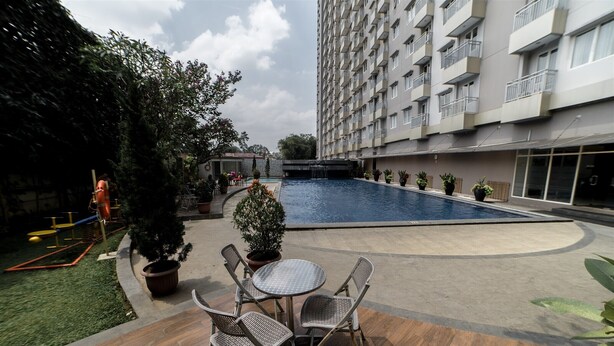 A courtyard with a swimming pool, outdoor seating, and a tall residential building. - Affordable Studio Galeri Ciumbuleuit 2 Apartment near Dago (Bandung)