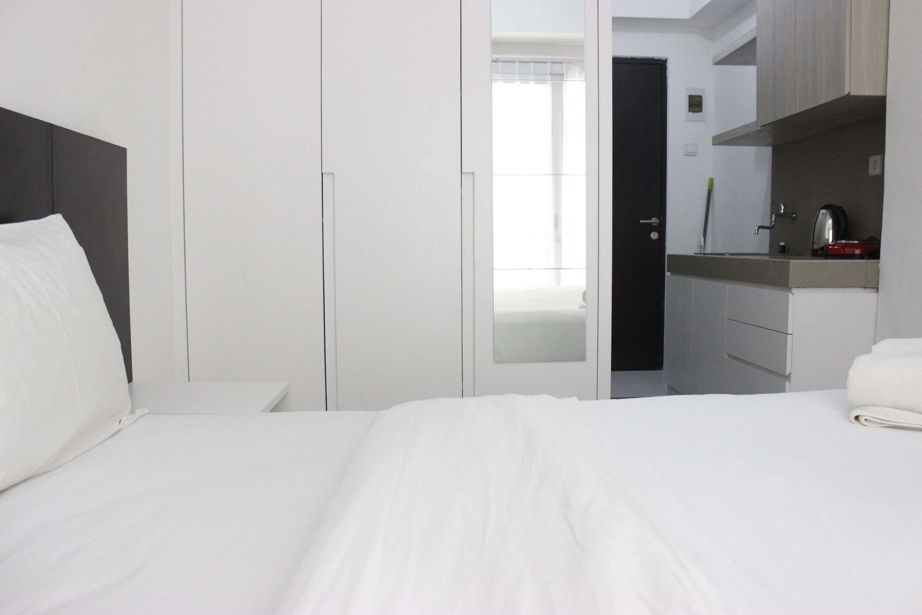Hotellihuone, jossa on sänky, yöpöytä, vaatekaappi ja pieni keittotila.