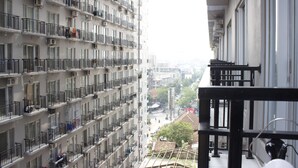 Un edificio de gran altura con varios balcones, unidades de aire acondicionado y vista de la calle.