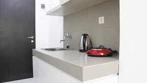 Una cocina moderna con una encimera, un fregadero, un hervidor y un electrodoméstico rojo.