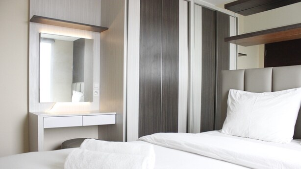 A hotel room with a bed, a bedside table, a mirror, and a headboard. - Brand New 2BR @ Tamansari La Grande Apartment Bandung (Bandung)