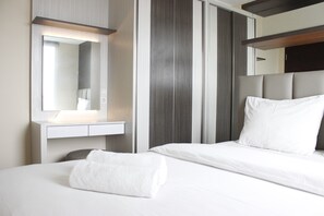 A hotel room with a bed, a bedside table, a mirror, and a headboard. - Brand New 2BR @ Tamansari La Grande Apartment Bandung (Bandung)
