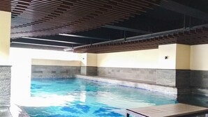 An indoor swimming pool with a tiled floor and a bench. - Brand New 2BR @ Tamansari La Grande Apartment Bandung (Bandung)