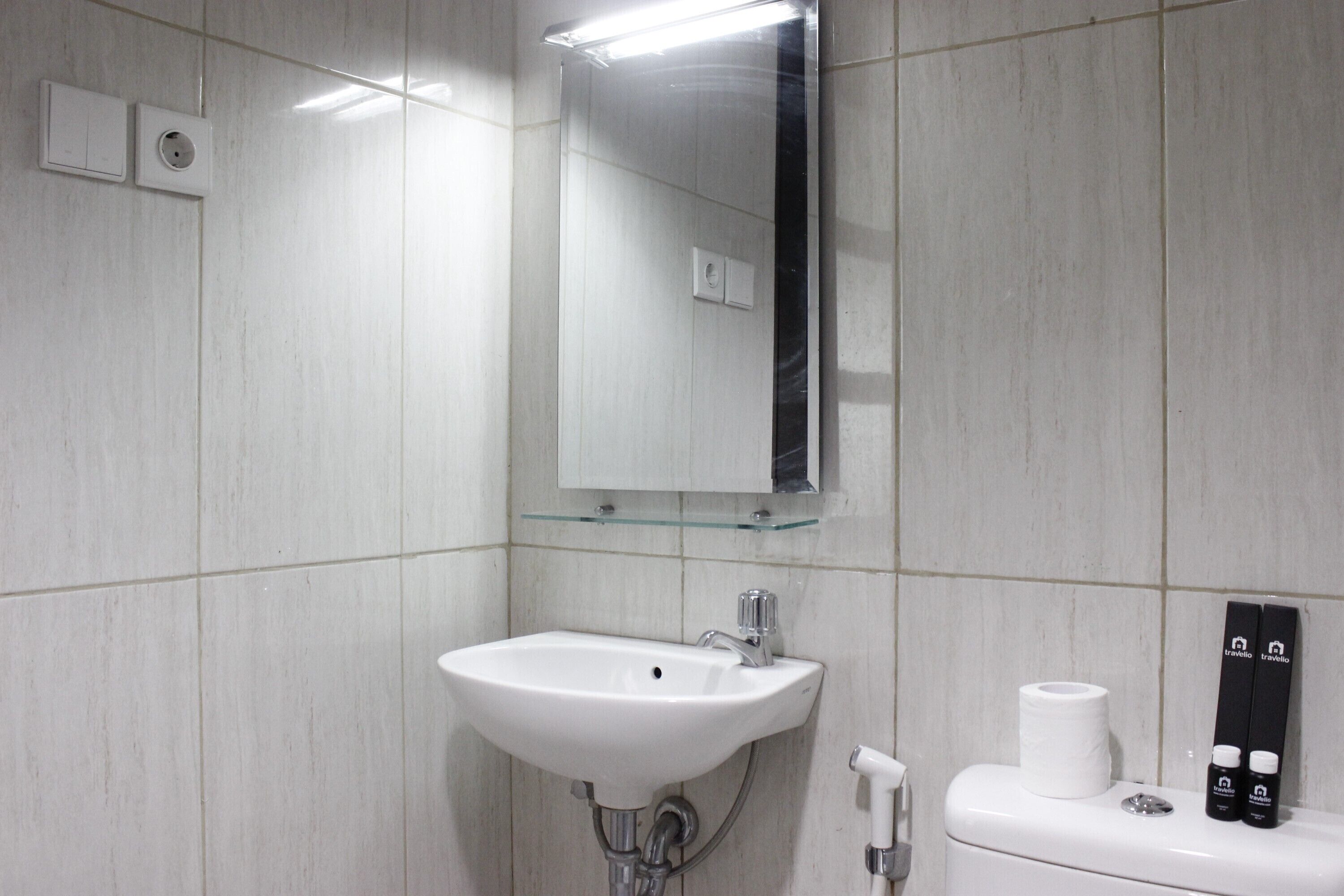 A bathroom with a white sink, a mirror, and a toilet.