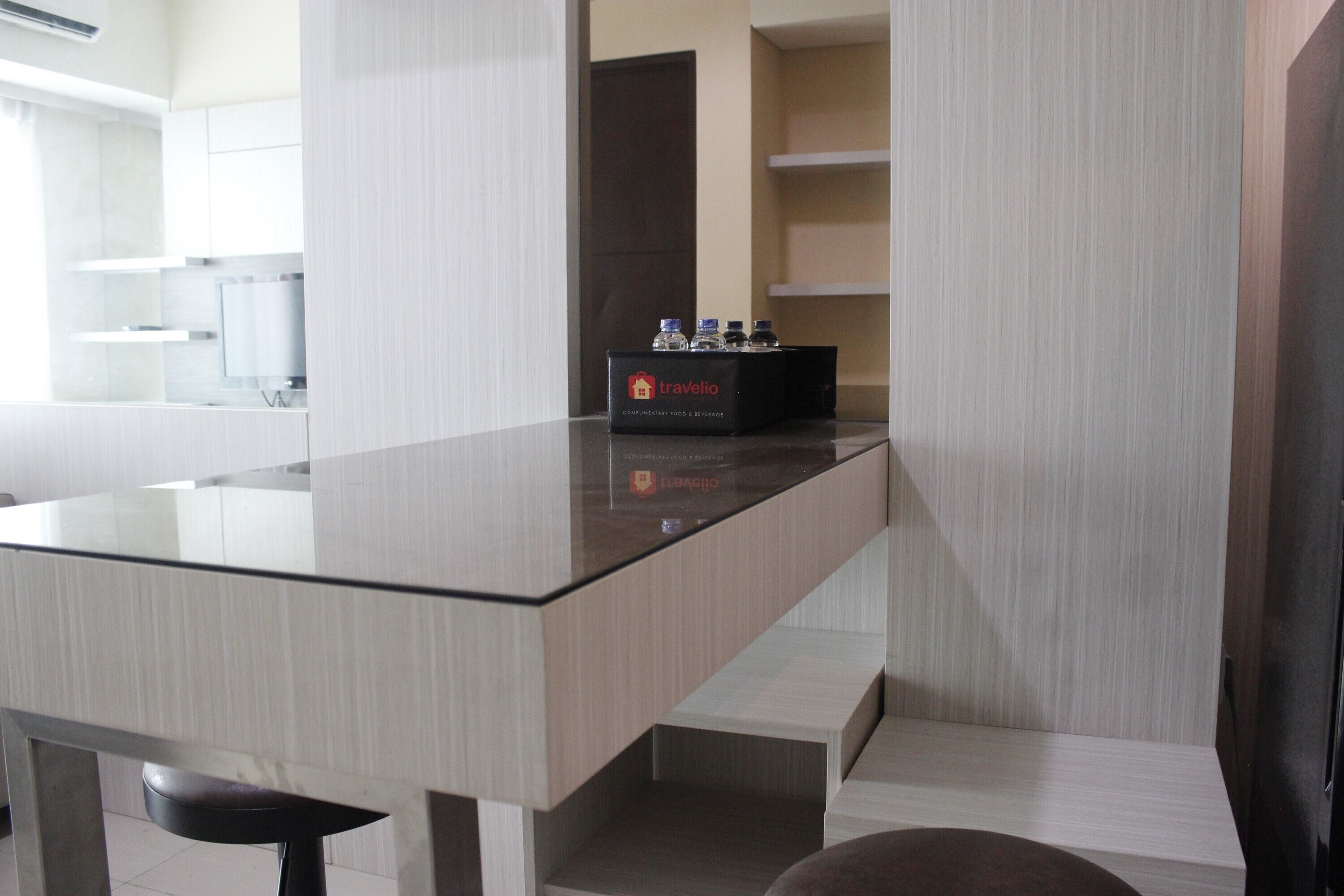 A modern kitchen with a glass countertop, a black box labeled 'travelio', and a dark-colored chair.