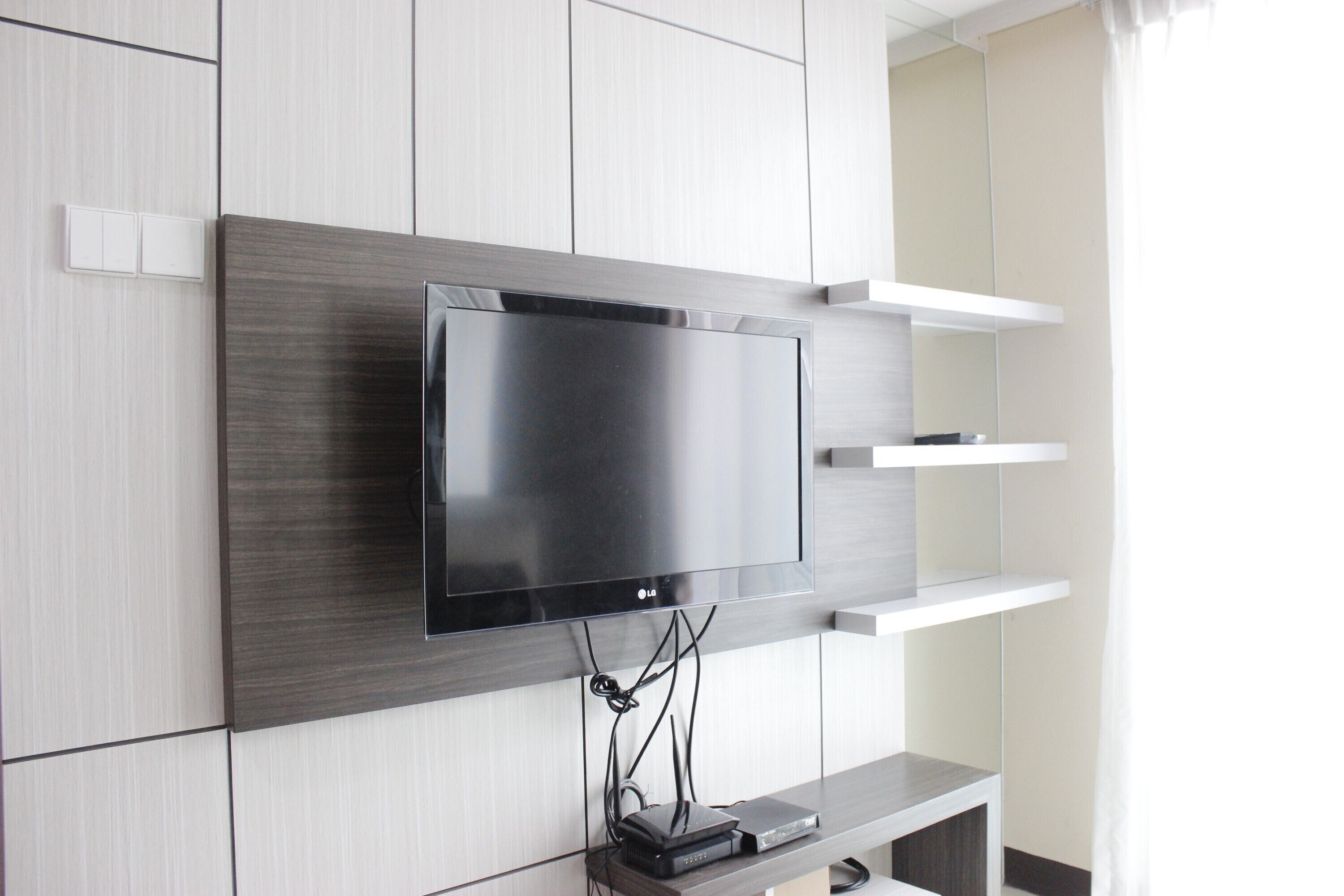 Una sala de estar moderna con un televisor de pantalla plana montado en la pared, un mueble empotrado debajo y un diseño minimalista.