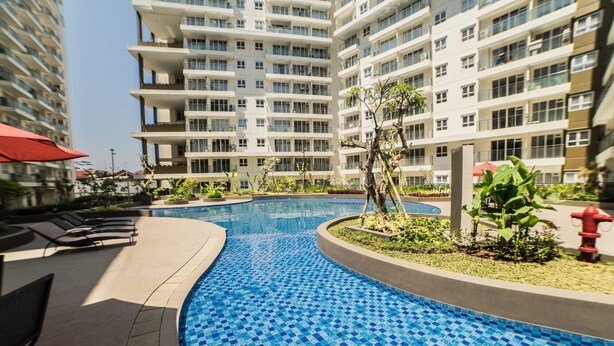 A swimming pool with blue mosaic tiles, surrounded by a low wall and plants. - Scenic & Trendy Studio Apartment at Gateway Pasteur (Cimahi)
