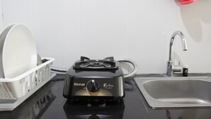 A kitchen with a Rinnai gas stove, a sink, and a dish rack. - Scenic & Trendy Studio Apartment at Gateway Pasteur (Cimahi)