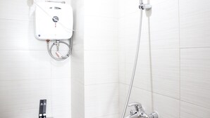 A modern bathroom with a wall-mounted water heater, a handheld showerhead, and a separate faucet. - Cozy & Trendy Studio at Gateway Pasteur Apartment (Cimahi)
