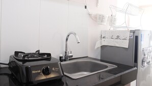 A compact kitchen with a gas stove, stainless steel sink, and a refrigerator. - Cozy & Trendy Studio at Gateway Pasteur Apartment (Cimahi)