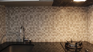 A kitchen with a checkered tile backsplash, a stainless steel sink, and a gas stove. - Elegant 2BR Gateway Pasteur Apartment near Exit Toll Pasteur (Cimahi)