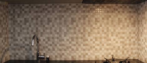 A kitchen with a checkered tile backsplash, a stainless steel sink, and a gas stove.
