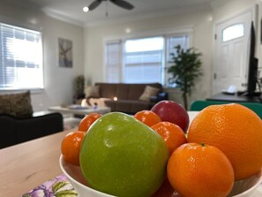 Una sala de estar con una mesa de comedor en primer plano, un sofá y un televisor al fondo.