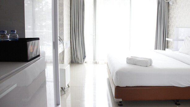 A hotel room with a bed, a TV, and a minibar. - Relaxing Studio near ITB at Beverly Dago Apartment (Bandung)