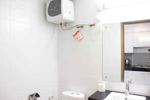 Um banheiro moderno com azulejos brancos, vaso sanitário, pia e secador de mãos.