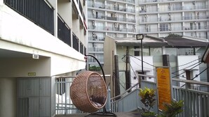 A balcony with a wicker chair, a potted plant, and a sign indicating a view of the sea. - Relaxing Studio near ITB at Beverly Dago Apartment (Bandung)