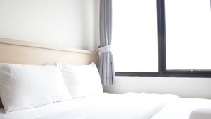 Una cama bien hecha con sábanas blancas en una habitación con cabecera de madera y una ventana con cortinas.