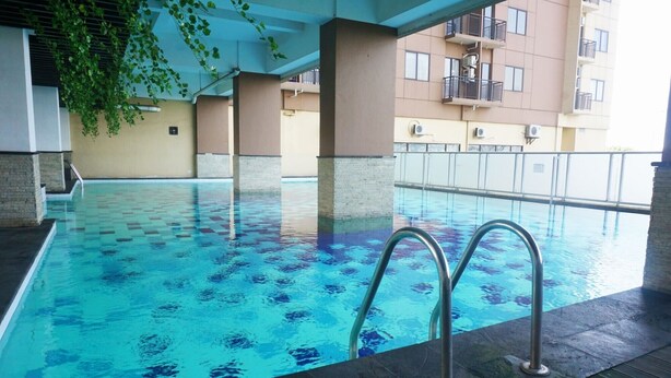 Una piscina interior con agua azul cristalina, suelo de baldosas y barandillas de metal.