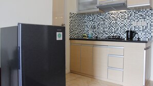 Cocina compacta con refrigerador de acero inoxidable, salpicadero de azulejos y muebles de madera.