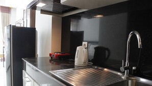 A modern kitchen with a stainless steel sink, a kettle, and a red appliance on the counter. - Strategic Studio at Green Kosambi Bandung Apartment (Bandung)