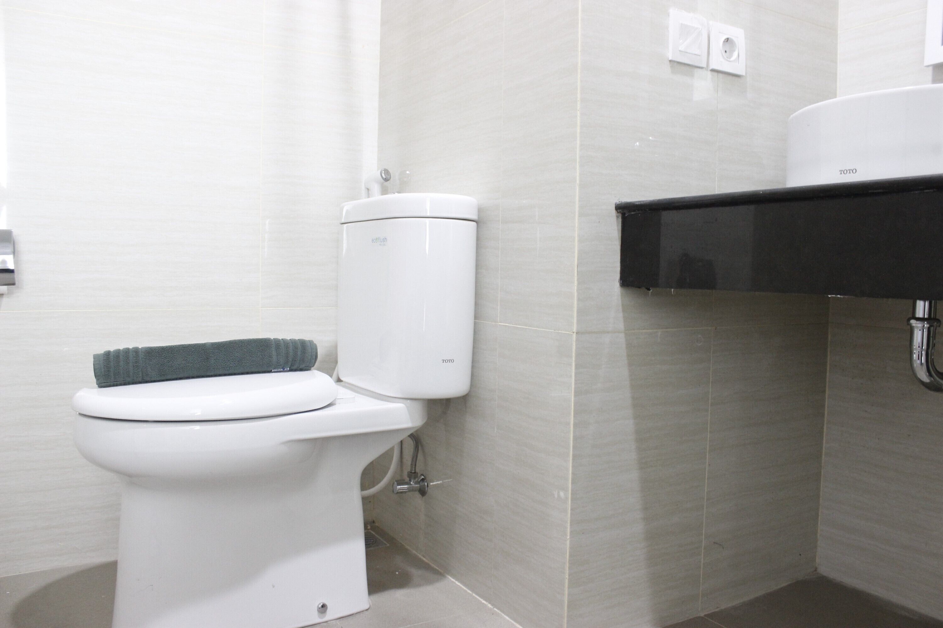 A modern bathroom with a white toilet, a towel rack, and a black sink.