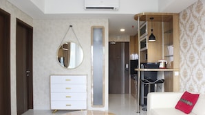 Una sala de estar moderna con un sofá blanco, una mesa de centro redonda de madera, un aparador blanco con pomos dorados, un espejo y una estantería empotrada.