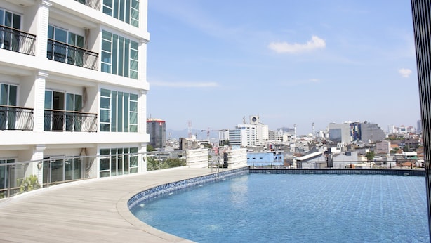 Un edificio moderno con piscina en la azotea y un paisaje urbano al fondo.