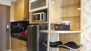 Una cocina moderna con microondas integrado, refrigerador y una barra con taburetes.